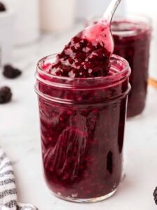 jar of blackberry jam with a spoon it it.