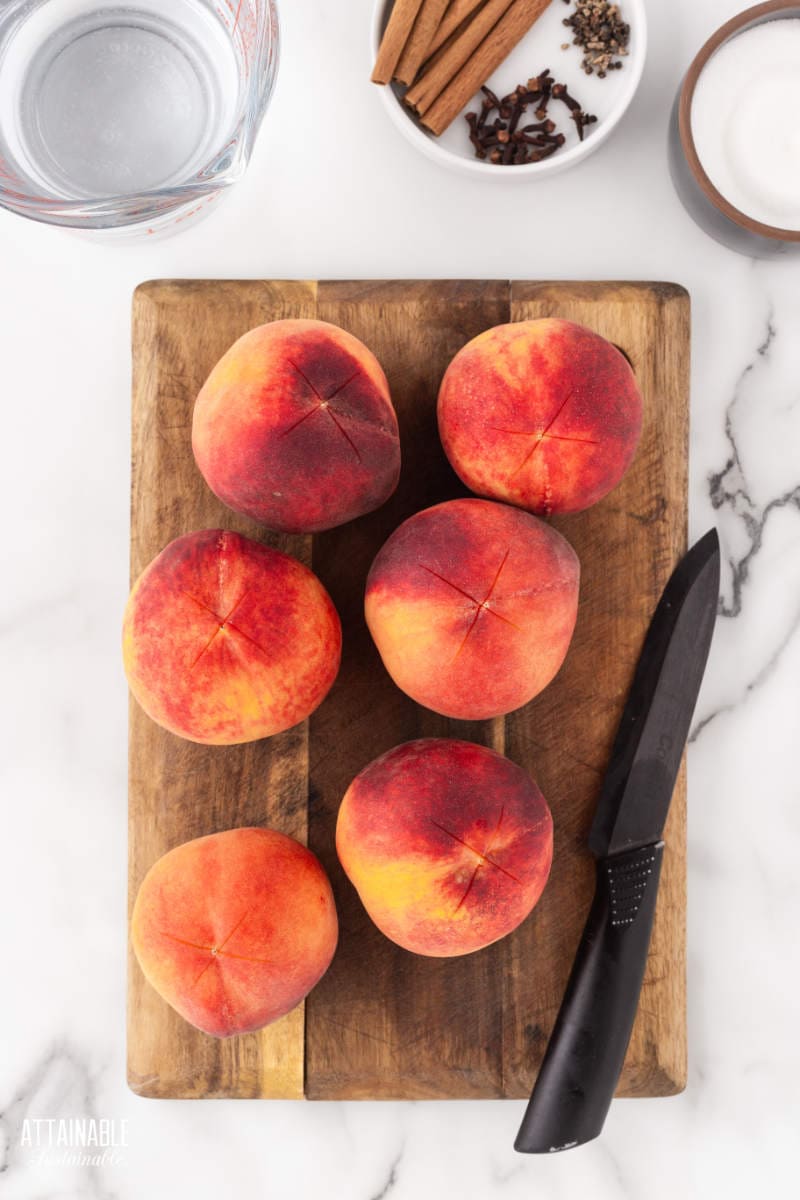 6 peaches on a wooden cutting board.